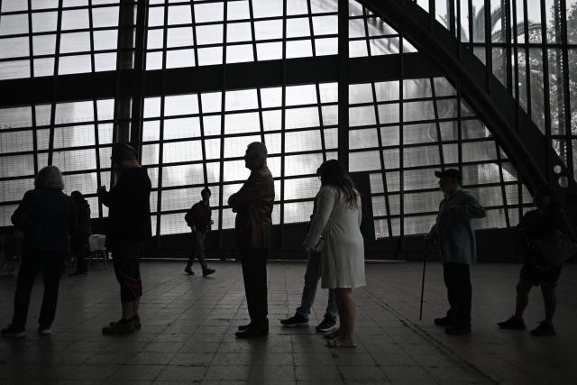 People queue to vote during the presidential runoff election at Estacion Mapocho in Santiago on December 14, 2025. Chileans head to the polls for a presidential runoff between Jeannette Jara, a communist backed by a broad left coalition, and Jose Antonio Kast, a devout far-right politico promising a hard line on security and migration. (Photo by Eitan ABRAMOVICH / AFP)