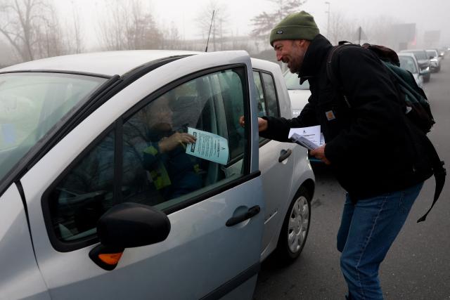 Guest A farmer gives a flyer to a motorist near the Carrefour des Rives d'Arcins shopping center to protest against the health policy put in place to eradicate lumpy skin disease affecting cattle in Bègles, suburb near Bordeaux, south-western France, on December 14, 2025. On December 12, 2025 French veterinarians slaughtered a herd of cows thought to be diseased after police dispersed angry farmers trying to protect them, an AFP reporter said, as an agricultural union called for nationwide protests. French farmers are unhappy with the state's management of an outbreak of nodular dermatitis -- widely known as lumpy skin disease. (Photo by ROMAIN PERROCHEAU / AFP)