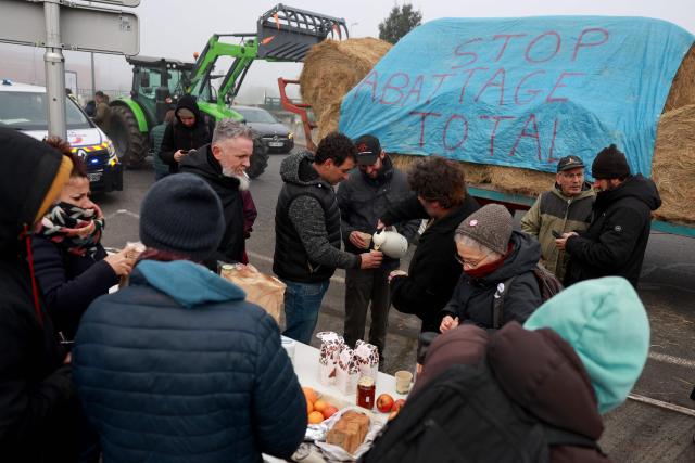 Farmers stand next to a banner reading "stop total slaughter" as they filter the access to the Rives d'Arcins shopping center in Bègles, on the outskirts of Bordeaux, south-western France, on December 14, 2025, to protest against the health policy put in place to eradicate lumpy skin disease affecting cattle. On December 12, 2025 French veterinarians slaughtered a herd of cows thought to be diseased after police dispersed angry farmers trying to protect them, an AFP reporter said, as an agricultural union called for nationwide protests. French farmers are unhappy with the state's management of an outbreak of nodular dermatitis -- widely known as lumpy skin disease. (Photo by ROMAIN PERROCHEAU / AFP)