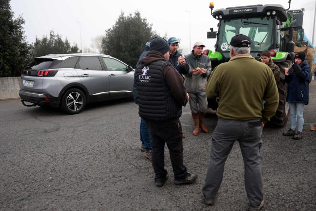 Farmers eat while they filter the access to the Rives d'Arcins shopping center in Bègles, on the outskirts of Bordeaux, south-western France, on December 14, 2025, to protest against the health policy put in place to eradicate lumpy skin disease affecting cattle. On December 12, 2025 French veterinarians slaughtered a herd of cows thought to be diseased after police dispersed angry farmers trying to protect them, an AFP reporter said, as an agricultural union called for nationwide protests. French farmers are unhappy with the state's management of an outbreak of nodular dermatitis -- widely known as lumpy skin disease. (Photo by ROMAIN PERROCHEAU / AFP)