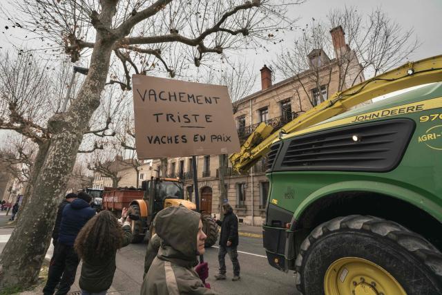A woman holds a sign that reads "Very sad - cows at peace" during a farmers' protest against the policy of slaughtering cows with Contagious Nodular Dermatosis (CND) in front of the sub-prefecture in Millau, central France, on December 14, 2025. On December 12, 2025 French veterinarians slaughtered a herd of cows thought to be diseased after police dispersed angry farmers trying to protect them, an AFP reporter said, as an agricultural union called for nationwide protests. French farmers are unhappy with the state's management of an outbreak of nodular dermatitis -- widely known as lumpy skin disease. (Photo by Idriss Bigou-Gilles / AFP)