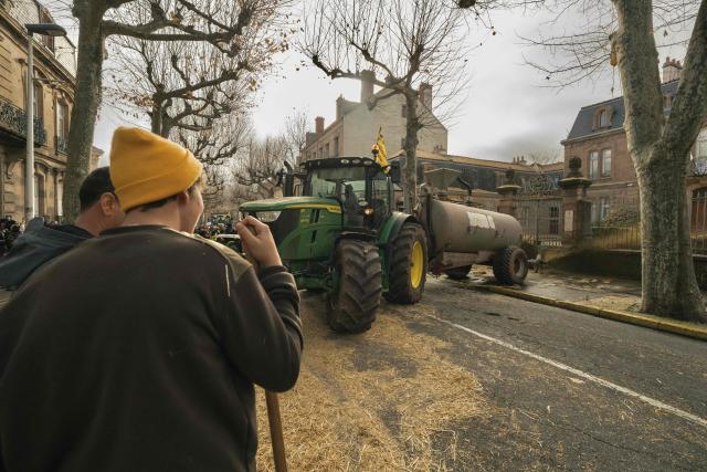 A tractor sprays liquid manure on the facade of Millau's sub-prefecture during a farmers' protest against the policy of slaughtering cows with Contagious Nodular Dermatosis (CND) in Millau, central France, on December 14, 2025. On December 12, 2025 French veterinarians slaughtered a herd of cows thought to be diseased after police dispersed angry farmers trying to protect them, an AFP reporter said, as an agricultural union called for nationwide protests. French farmers are unhappy with the state's management of an outbreak of nodular dermatitis -- widely known as lumpy skin disease. (Photo by Idriss Bigou-Gilles / AFP)