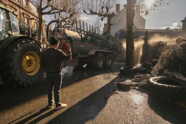 A tractor sprays liquid manure on the facade of Millau's sub-prefecture during a farmers' protest against the policy of slaughtering cows with Contagious Nodular Dermatosis (CND) in Millau, central France, on December 14, 2025. On December 12, 2025 French veterinarians slaughtered a herd of cows thought to be diseased after police dispersed angry farmers trying to protect them, an AFP reporter said, as an agricultural union called for nationwide protests. French farmers are unhappy with the state's management of an outbreak of nodular dermatitis -- widely known as lumpy skin disease. (Photo by Idriss Bigou-Gilles / AFP)