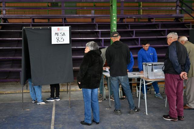 People queue to vote during the presidential runoff election in Santiago on December 14, 2025. Chileans head to the polls for a presidential runoff between Jeannette Jara, a communist backed by a broad left coalition, and Jose Antonio Kast, a devout far-right politico promising a hard line on security and migration. (Photo by RODRIGO ARANGUA / AFP)