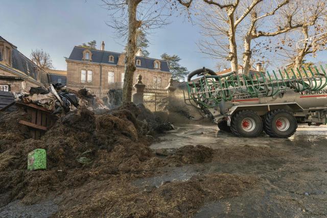A tractor sprays liquid manure on the facade of Millau's sub-prefecture during a farmers' protest against the policy of slaughtering cows with Contagious Nodular Dermatosis (CND) in Millau, central France, on December 14, 2025. On December 12, 2025 French veterinarians slaughtered a herd of cows thought to be diseased after police dispersed angry farmers trying to protect them, an AFP reporter said, as an agricultural union called for nationwide protests. French farmers are unhappy with the state's management of an outbreak of nodular dermatitis -- widely known as lumpy skin disease. (Photo by Idriss Bigou-Gilles / AFP)