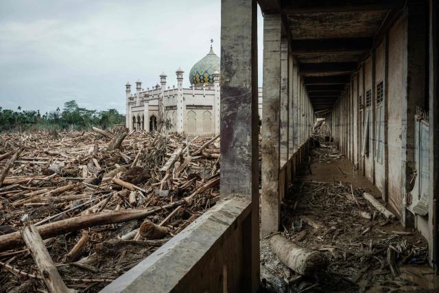 Piles of uprooted trees swept away by a flash flood about three weeks ago remain at Darul Mukhlisin Islamic Boarding School and its attached mosque in Aceh Tamiang, Northern Sumatra, on December 14, 2025. Devastating floods and landslides have killed 1,006 people in Indonesia, rescuers said on December 13 as the Southeast Asian nation grapples with the huge scale of relief efforts. (Photo by Yasuyoshi CHIBA / AFP)
