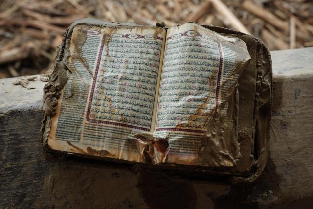 A Koran smeared in sludge is pictured after a flash flood at Darul Mukhlisin Islamic Boarding School and the mosque attached to the school in Aceh Tamiang, Northern Sumatra, on December 14, 2025. Devastating floods and landslides have killed 1,006 people in Indonesia, rescuers said on December 13 as the Southeast Asian nation grapples with the huge scale of relief efforts. (Photo by Yasuyoshi CHIBA / AFP)