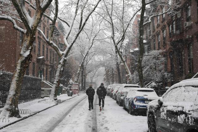 Pepole walk in a snow-covered street in the Brooklyn borough of New York City on December 14, 2025. (Photo by ANGELA WEISS / AFP)