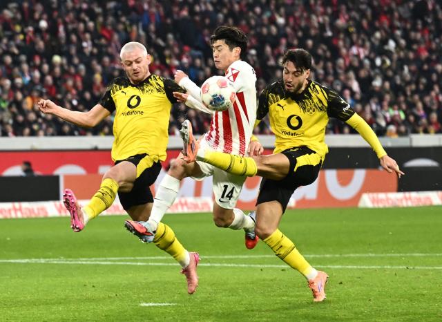 (L-R) Dortmund's Norwegian defender #26 Julian Ryerson, Freiburg's Japanese midfielder #14 Yuito Suzuki and Dortmund's Algerian defender #05 Ramy Bensebaini vie for the ball during the German first division Bundesliga football match between SC Freiburg and BVB Bosussia Dortmund in Freiburg, southwestern Germany on December 14, 2025. (Photo by Silas STEIN / AFP) / DFL REGULATIONS PROHIBIT ANY USE OF PHOTOGRAPHS AS IMAGE SEQUENCES AND/OR QUASI-VIDEO