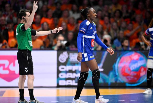 France's pivot #29 Onacia Ondono (R) leaves the pitch as she is signaled a two-minute penalty by the referee during the IHF Women's Handball World Championship match for 3rd place between the Netherlands and France at the Rotterdam Ahoy Arena, in Rotterdam on December 14, 2025. (Photo by JOHN THYS / AFP)