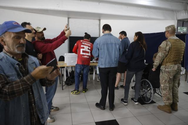 People queue to vote during the presidential runoff election at Monumental Colo-Colo Stadium in Santiago, Chile on December 14, 2025. Chileans head to the polls for a presidential runoff between Jeannette Jara, a communist backed by a broad left coalition, and Jose Antonio Kast, a devout far-right politico promising a hard line on security and migration. (Photo by Raul BRAVO / AFP)