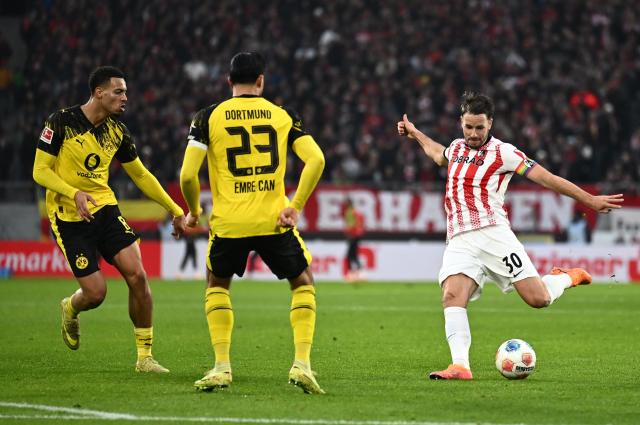 (L-R) Dortmund's German midfielder #08 Felix Nmecha, Dortmund's German midfielder #23 Emre Can and Freiburg's German defender #30 Christian Guenter vie for the ball during the German first division Bundesliga football match between SC Freiburg and BVB Bosussia Dortmund in Freiburg, southwestern Germany on December 14, 2025. (Photo by Silas STEIN / AFP) / DFL REGULATIONS PROHIBIT ANY USE OF PHOTOGRAPHS AS IMAGE SEQUENCES AND/OR QUASI-VIDEO