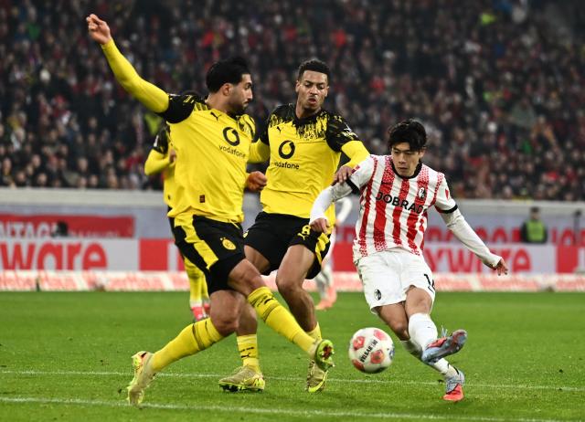 (L-R) Dortmund's German midfielder #23 Emre Can, Dortmund's German midfielder #08 Felix Nmecha and Freiburg's Japanese midfielder #14 Yuito Suzuki vie for the ball during the German first division Bundesliga football match between SC Freiburg and BVB Bosussia Dortmund in Freiburg, southwestern Germany on December 14, 2025. (Photo by Silas STEIN / AFP) / DFL REGULATIONS PROHIBIT ANY USE OF PHOTOGRAPHS AS IMAGE SEQUENCES AND/OR QUASI-VIDEO