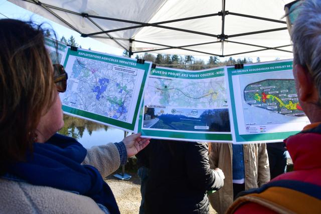 Protestors look at documents about the project road as they take part in a march organised by "collectif Alouettes 147" against the project of a new road (2x2 between Couzeix and Nieul), in Nieul, central France on December 14, 2025. (Photo by PASCAL LACHENAUD / AFP)