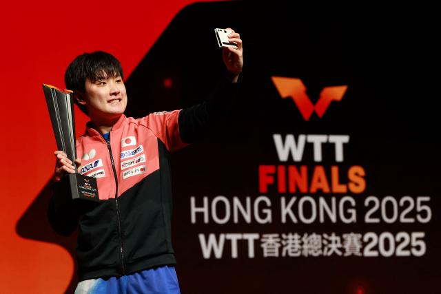 TOPSHOT - Japan’s Tomokazu Harimoto holds the winner's trophy after his victory in the men’s singles final match during the World Table Tennis (WTT) finals at the Hong Kong Coliseum in Hong Kong on December 14, 2025. (Photo by May JAMES / AFP)