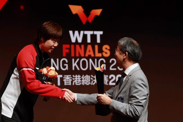 China’s Kuai Man receives the secondary trophy following the women’s singles final match during the World Table Tennis (WTT) finals at the Hong Kong Coliseum in Hong Kong on December 14, 2025. (Photo by May JAMES / AFP)