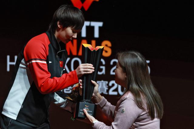 China’s Wang Manyu receives the winner's trophy following the women’s singles final match during the World Table Tennis (WTT) finals at the Hong Kong Coliseum in Hong Kong on December 14, 2025. (Photo by May JAMES / AFP)