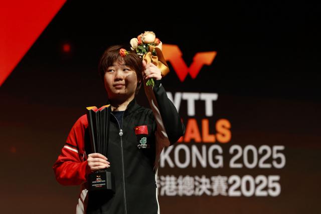 China’s Kuai Man holds the secondary trophy following the women’s singles final match during the World Table Tennis (WTT) finals at the Hong Kong Coliseum in Hong Kong on December 14, 2025. (Photo by May JAMES / AFP)