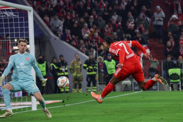 Bayern Munich's German forward #07 Serge Gnabry attempts to score past Mainz' German goalkeeper #33 Daniel Batz during the German first division Bundesliga football match between FC Bayern Munich and Mainz 05 in Munich, southern Germany on December 14, 2025. (Photo by Karl-Josef HILDENBRAND / AFP) / DFL REGULATIONS PROHIBIT ANY USE OF PHOTOGRAPHS AS IMAGE SEQUENCES AND/OR QUASI-VIDEO