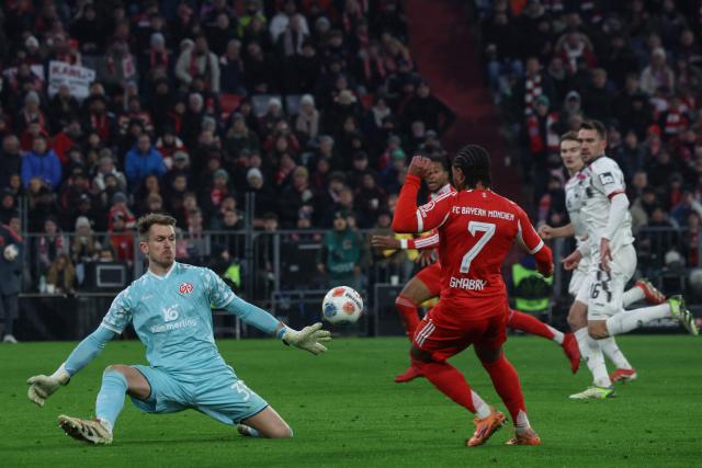 Bayern Munich's German forward #07 Serge Gnabry attempts to score past Mainz' German goalkeeper #33 Daniel Batz during the German first division Bundesliga football match between FC Bayern Munich and Mainz 05 in Munich, southern Germany on December 14, 2025. (Photo by Karl-Josef HILDENBRAND / AFP) / DFL REGULATIONS PROHIBIT ANY USE OF PHOTOGRAPHS AS IMAGE SEQUENCES AND/OR QUASI-VIDEO