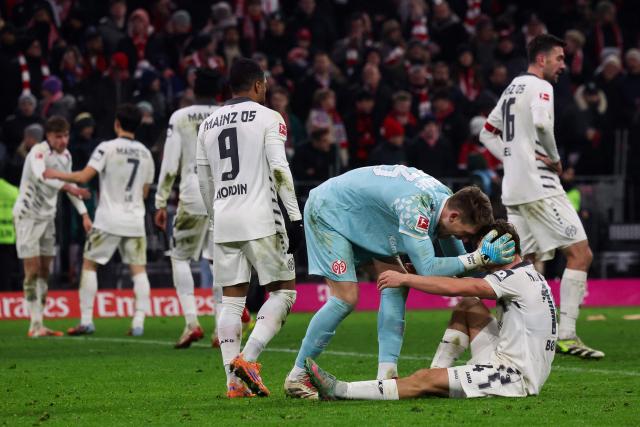 Mainz' German goalkeeper #33 Daniel Batz and Mainz' Danish forward #14 William Boeving embrace after the German first division Bundesliga football match between FC Bayern Munich and Mainz 05 in Munich, southern Germany on December 14, 2025. (Photo by Karl-Josef HILDENBRAND / AFP) / DFL REGULATIONS PROHIBIT ANY USE OF PHOTOGRAPHS AS IMAGE SEQUENCES AND/OR QUASI-VIDEO