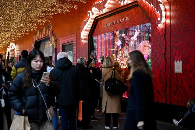 Pedestrians walk past the Galeries Lafayette, days before Christmas, in Paris on December 14, 2025. (Photo by Anna KURTH / AFP)