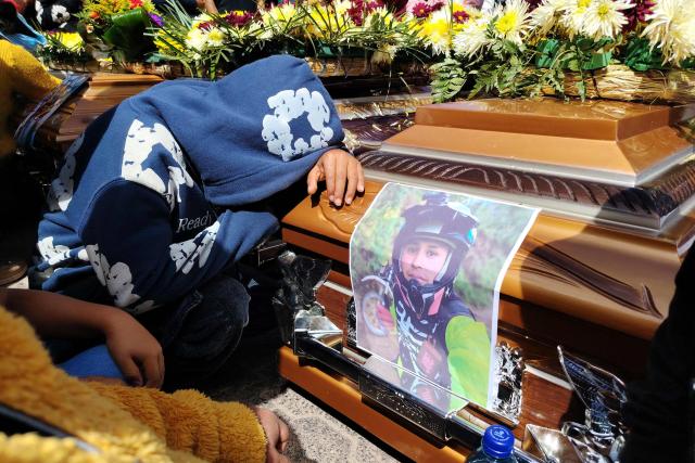 TOPSHOT - A person mourns beside the coffin of a victim of an armed confrontation in Nahuala, Solola department, Guatemala on December 14, 2025. The Guatemalan government restricted certain civil rights for 15 days in the indigenous region where at least five people were shot dead on December 13, 2025, President Bernardo Arevalo announced a day after. Solola, west of Guatemala City, has been the scene of clashes for years over a land dispute between the indigenous communities of Santa Catarina Ixtahuacan and Nahuala. (Photo by AFP)