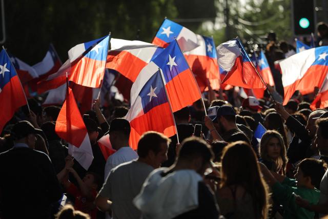 Supporters of Chile's presidential candidate Jose Antonio Kast, of the Partido Republicano party, wave national flags following the first results of the presidential runoff election in Santiago on December 14, 2025. (Photo by Javier TORRES / AFP)