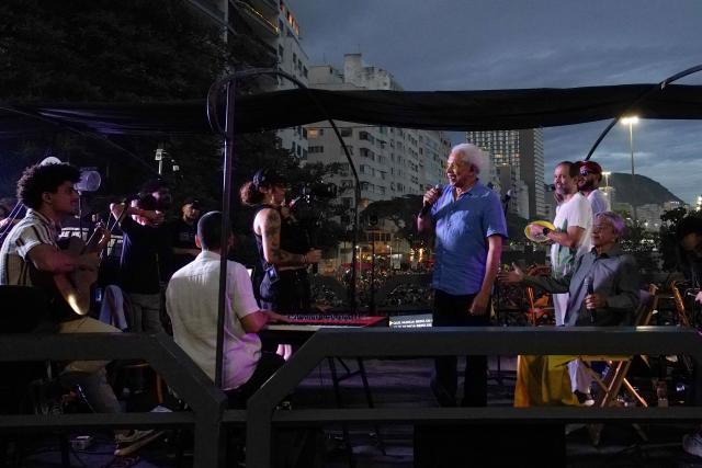 Brazilian artist Paulinho da Viola (C) and Caetano Veloso (R) perform during a protest calling for no amnesty for coup attempt in the case against former Brazilian president Jair Bolsonaro at Copacabana beach in Rio de Janeiro, Brazil, on December 14, 2025. (Photo by MAURO PIMENTEL / AFP)