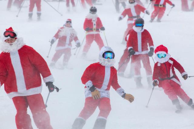 People dressed in Santa Claus costumes ski down South Ridge at Sunday River resort in Newry Maine, on Sunday, December 14, 2025, to raise money for The River Fund and the Boyne Forever Foundation. (Photo by Lauren OWENS LAMBERT / AFP)