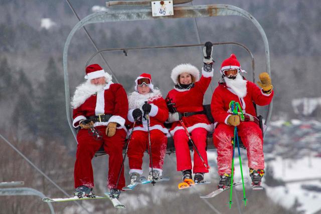 People dressed in Santa Claus costumes ride up the chairlift at South Ridge at Sunday River resort in Newry Maine, on Sunday, December 14, 2025, to raise money for The River Fund and the Boyne Forever Foundation. (Photo by Lauren OWENS LAMBERT / AFP)