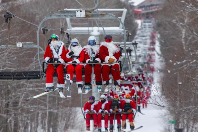 People dressed in Santa Claus costumes ride up the chairlift at South Ridge at Sunday River resort in Newry Maine, on Sunday, December 14, 2025, to raise money for The River Fund and the Boyne Forever Foundation. (Photo by Lauren OWENS LAMBERT / AFP)
