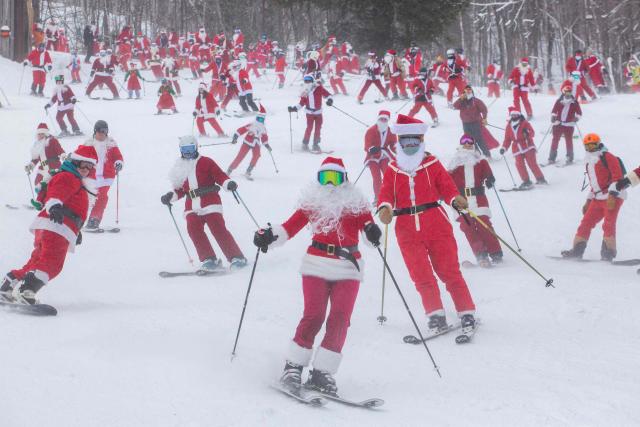 People dressed in Santa Claus costumes ski down South Ridge at Sunday River resort in Newry Maine, on Sunday, December 14, 2025, to raise money for The River Fund and the Boyne Forever Foundation. (Photo by Lauren OWENS LAMBERT / AFP)