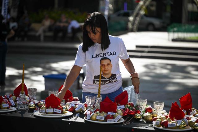 A relative of political prisoners sets a Christmas table during a demonstration called “The table of those who wait,” demanding their release, at Bolнvar Square in the Chacao municipality of Caracas on December 14, 2025. (Photo by Federico PARRA / AFP)