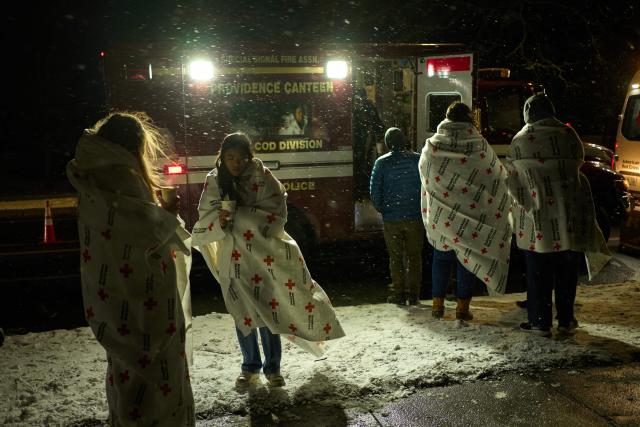 Brown University students try to stay warm with hot drinks and blankets during a candlelight vigil the following day of a mass shooting on the campus of Brown University, in Providence, Rhode Island on December 14, 2025. US authorities on Sunday detained a person of interest in the mass shooting at Brown University that left two people dead and nine others wounded, the latest in a long line of school attacks nationwide. (Photo by Bing Guan / AFP)