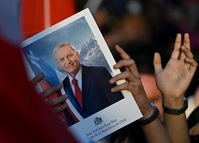A person shows a sign depicting Chile's presidential candidate Jose Antonio Kast, of the Partido Republicano party, that reads his name and "President of the Republic of Chile" following the first results of the presidential runoff election in Santiago on December 14, 2025. Chilean voters elected Jose Antonio Kast, the most right-wing president in 35 years of democracy, with a thumping 58 percent of votes and his rival Jeannette Jara conceding defeat, according to official results on December 14, 2025. (Photo by Eitan ABRAMOVICH / AFP)