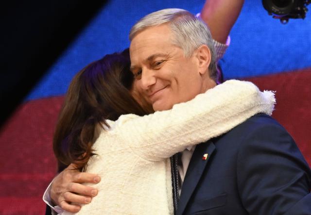 Chile's presidential candidate Jose Antonio Kast (R), of the Partido Republicano party, and his wife Maria Pia Adriasola (L) hug as they celebrate the results of the presidential runoff election in Santiago on December 14, 2025. Chilean voters elected Jose Antonio Kast, the most right-wing president in 35 years of democracy, with a thumping 58 percent of votes and his rival Jeannette Jara conceding defeat, according to official results on December 14, 2025. (Photo by Eitan ABRAMOVICH / AFP)
