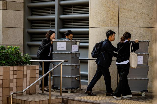 Court staff move exhibits into the West Kowloon Law Courts ahead of the expected verdicts in the national security trial of pro-democracy media tycoon Jimmy Lai in Hong Kong on December 15, 2025. Long-awaited verdicts in Hong Kong pro-democracy media tycoon Jimmy Lai's national security trial will be delivered on December 15, one of the city's most closely watched rulings since its return to Chinese rule in 1997. (Photo by Leung Man Hei / AFP)