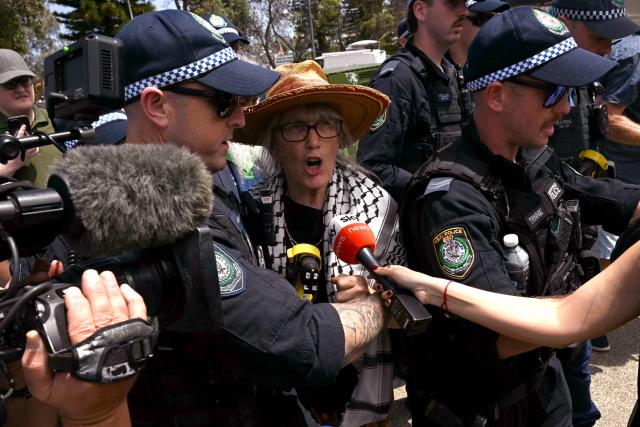 A pro-Palestinian supporter is escorted by police from the Bondi Beach area in Sydney on December 15, 2025, a day after the shootings. A father-and-son team toting long-barrelled guns shot and killed 15 people including a 10-year-old girl at Sydney's Bondi Beach on December 14, with authorities labelling it an antisemitic terrorist attack on a Jewish festival. (Photo by Saeed KHAN / AFP)