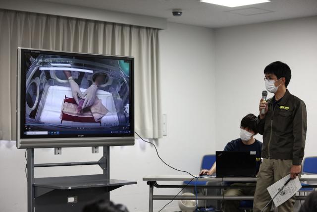 (FILE) Ueno Zoological Gardens staff Naoya Ohashi (R) shows an image of the first of two newly-born twin cubs delivered by giant panda Shin Shin at Tokyo's Ueno Zoo on June 23, 2021. Two pandas at a Tokyo zoo will be returned to China in January, Japanese media said on December 15, 2025, potentially leaving Japan without the beloved animals for the first time in half a century. (Photo by BEHROUZ MEHRI / AFP)