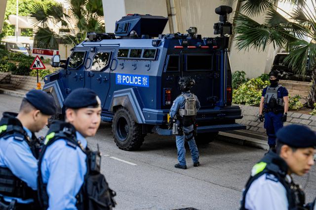Armed police keep watch beside an armoured vehicle outside the West Kowloon court where media tycoon Jimmy Lai's national security trial is being held in Hong Kong on December 15, 2025. Hong Kong pro-democracy media tycoon Jimmy Lai was on December 15 found guilty on two counts of foreign collusion and of seditious publication, in one of the Chinese city's highest-profile national security trials. (Photo by Leung Man Hei / AFP)