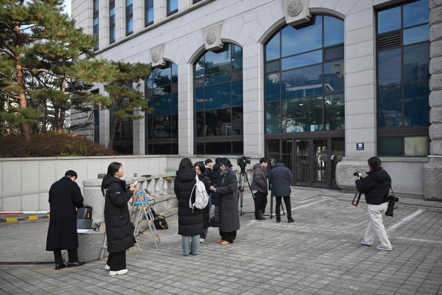 Reporters gather outside the headquarters of Unification Church in Seoul on December 15, 2025, as police raid the building. South Korean police raided the headquarters of the cult-like Unification church on December 15, and named its leader as a suspect in the bribery of several high-profile politicians. (Photo by Jung Yeon-je / AFP)