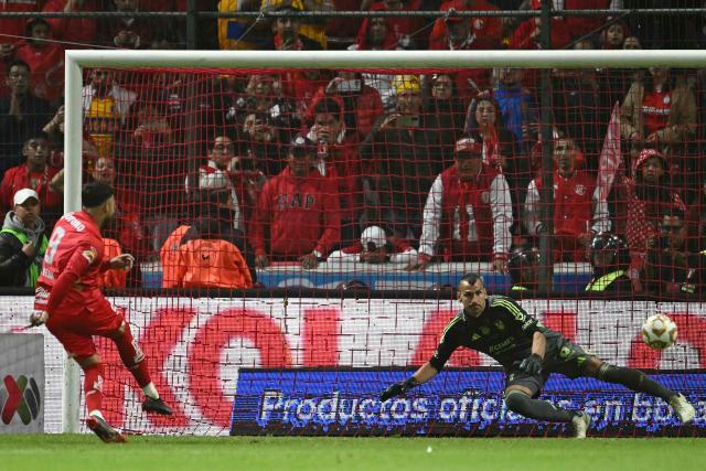 Toluca's forward #09 Alexis Vega shoots and scores against Tigres' Argentine goalkeeper #01 Nahuel Guzman during the penalty shootout of the Liga MX Apertura final second leg football match between Toluca and Tigres at the Nemesio Diez stadium in Toluca, Mexico on December 14, 2025. (Photo by Yuri CORTEZ / AFP)