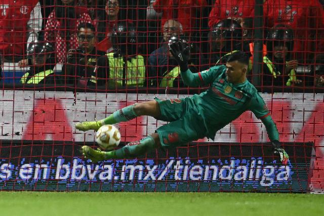 Toluca's goalkeeper #22 Luis Garcia makes a save past Tigres' Argentine goalkeeper #01 Nahuel Guzman during the penalty shootout of the Liga MX Apertura final second leg football match between Toluca and Tigres at the Nemesio Diez stadium in Toluca, Mexico on December 14, 2025. (Photo by Yuri CORTEZ / AFP)