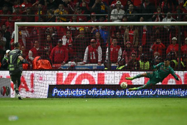 Toluca's goalkeeper #22 Luis Garcia makes a save past Tigres' Argentine goalkeeper #01 Nahuel Guzman during the penalty shootout of the Liga MX Apertura final second leg football match between Toluca and Tigres at the Nemesio Diez stadium in Toluca, Mexico on December 14, 2025. (Photo by Yuri CORTEZ / AFP)