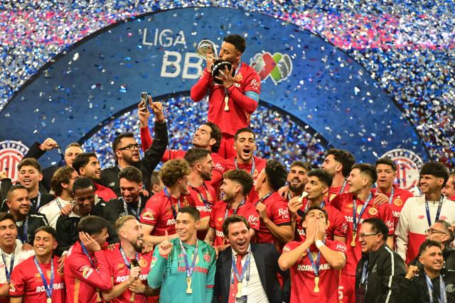 Toluca's forward #09 Alexis Vega kisses the trophy next to teammates after winning the Liga MX Apertura final second leg football match between Toluca and Tigres at the Nemesio Diez stadium in Toluca, Mexico on December 14, 2025. (Photo by Mario Vazquez / AFP)