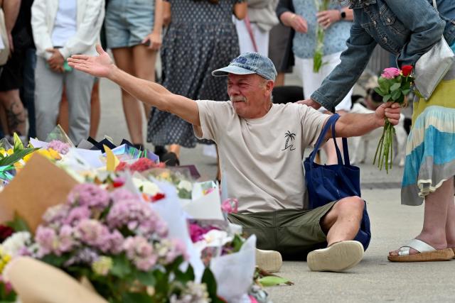 A mourner reacts as he pays a floral tribute to Bondi Beach shooting victims at the Bondi Pavilion in Sydney on December 15, 2025. A father-and-son team toting long-barrelled guns shot and killed 15 people including a 10-year-old girl at Sydney's Bondi Beach on December 14, with authorities labelling it an antisemitic terrorist attack on a Jewish festival. (Photo by Saeed KHAN / AFP)