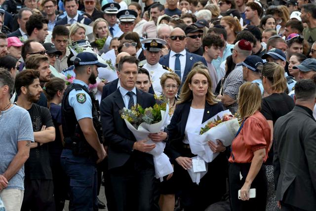 New South Wales Premier Chris Minns (centre, L) and Kellie Sloane (centre, R), Leader of the Opposition in New South Wales, lay flowers as a tribute at the Bondi Pavillion in memory of the victims of a shooting at Bondi Beach, in Sydney on December 15, 2025. A father and son opened fire on a Jewish festival at Australia's Bondi Beach in a shooting spree that killed 15 people, including a child, authorities said on December 15, denouncing the attack as antisemitic "terrorism". (Photo by Saeed KHAN / AFP)