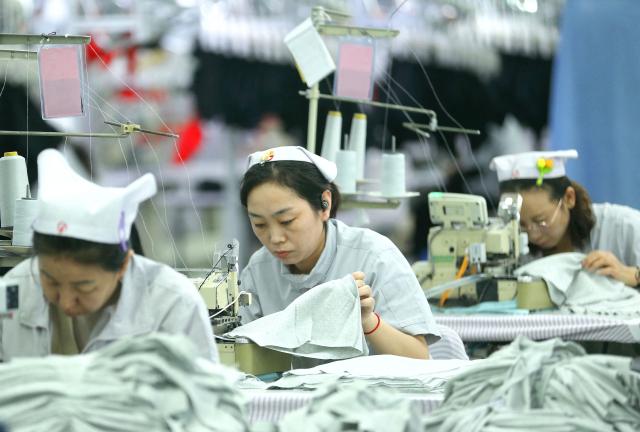 Workers sew garments at a textile factory in Qingdao, in eastern China's Shandong province on December 15, 2025. (Photo by AFP) / China OUT