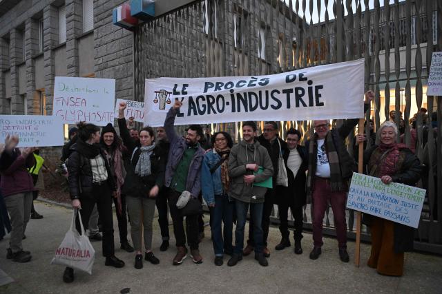 Defendants and their relatives hold banners and placards outside the Lorient courthouse ahead of the trial of 12 environmental activists from the Brittany Against Factory Farms collective for blocking a freight train in Lorient, western France, on December 15, 2025. (Photo by Damien MEYER / AFP)